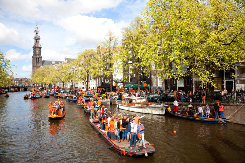Varen door de Amsterdamse grachten tijdens Koningsdag. Koningsdag, koninginnedag, vieren, typisch Hollands, Nederland, vieren, feest, festival, Amsterdam, oranje,