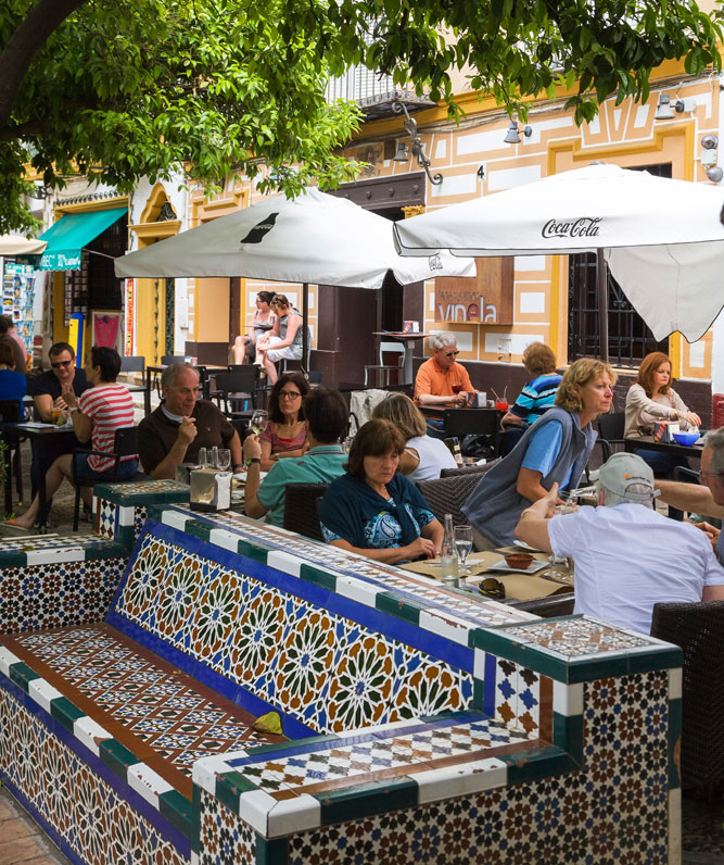 Having lunch under the orange trees at a square in the Santa Cruz area, city trip Sevilla