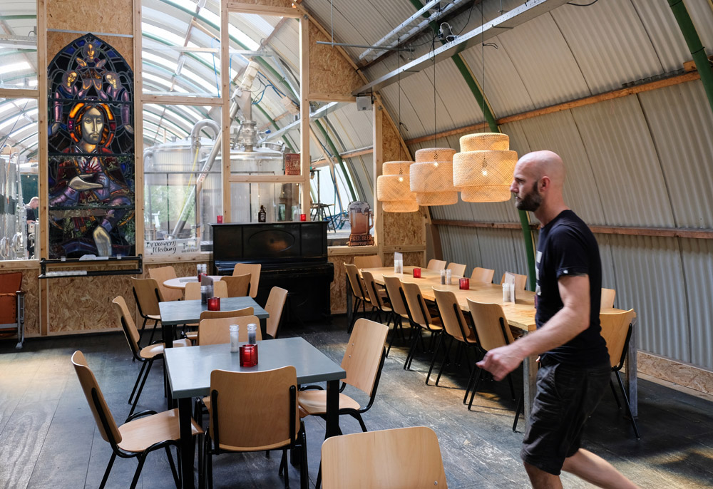 Een glazen wand scheidt het restaurant van de bierbrouwerij - microbierbrouwerij Kleiburg i Amsterdam Zuidoost waar kloosterbier gemaakt wordt. 