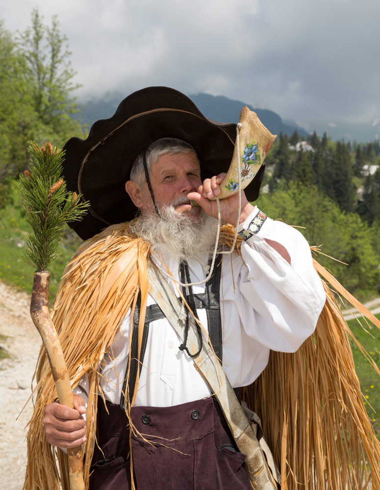 Andre speelt een deuntje op een koeienhoorn, Wandelen op het plateau Velika planina nabij de stad Kamnik in Slovenie