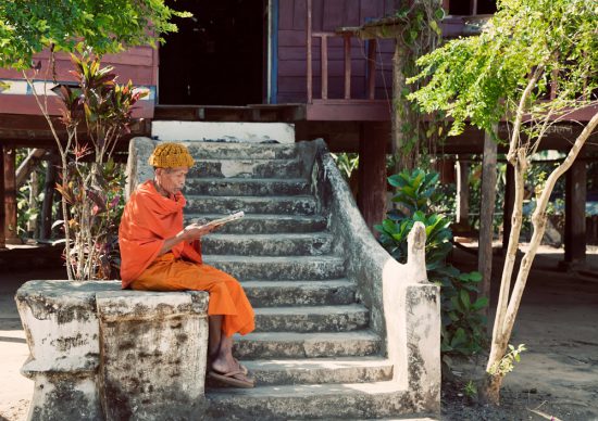 Een monnik leest op de trappen van de tempel. Rondreis Thailand en Laos