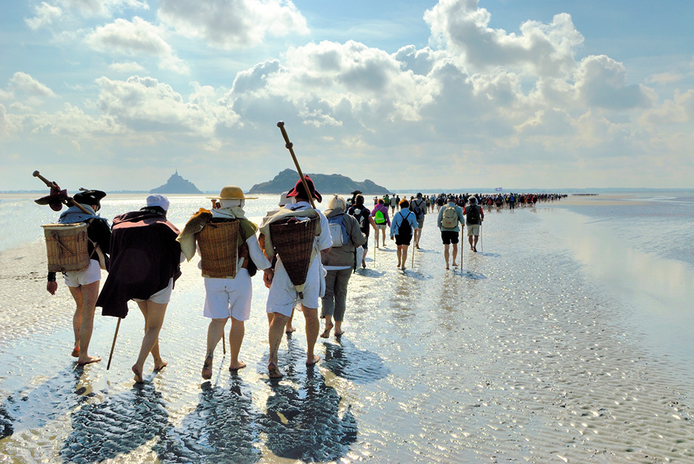 Wandelen op de zeebodem in de baai van Mont-Saint-Michel. Foto: Yvon Boelle-CRT-Normandie. Brochure Duurzaam op vakantie in Frankrijk