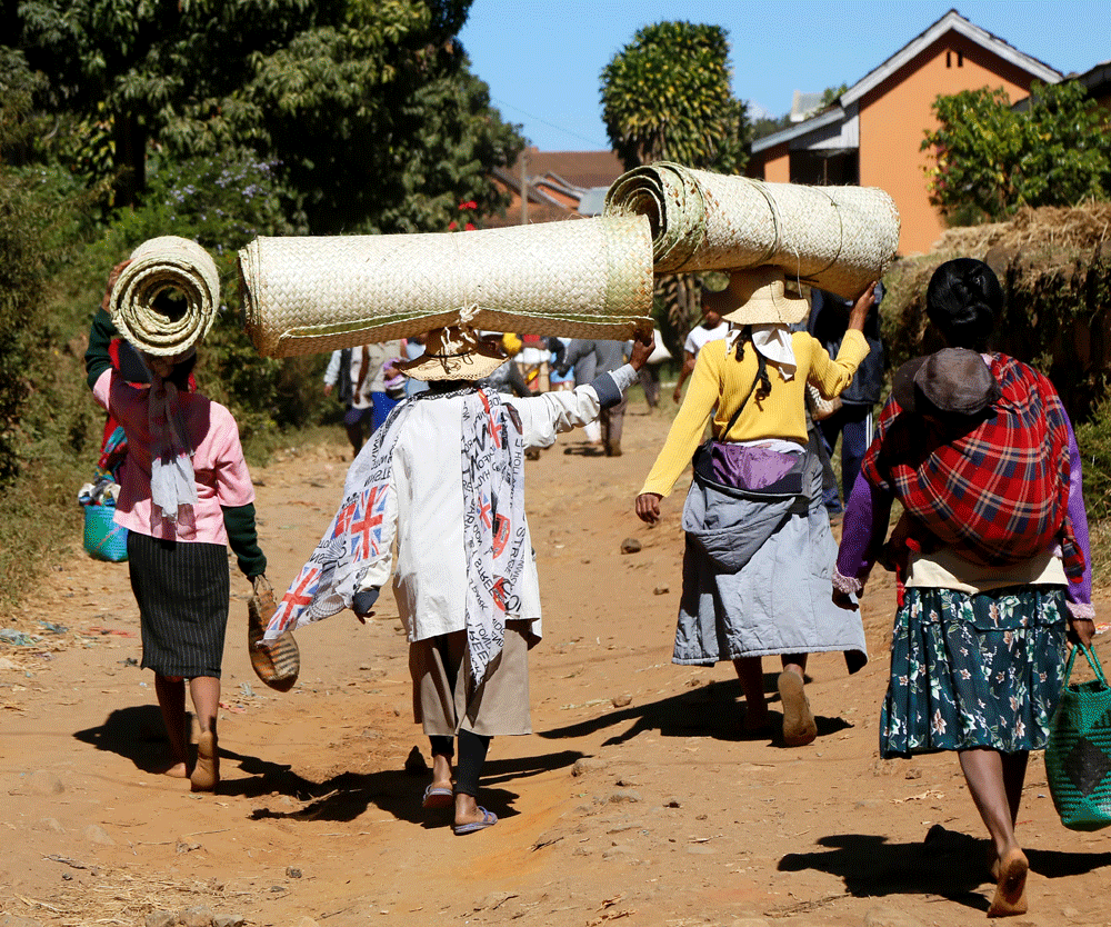 Met de aankopen op hun hoofd gaan de mensen huiswaarts. Rondreis Madagaskar, wnadelen in de buurt van Betafo. Hiken.